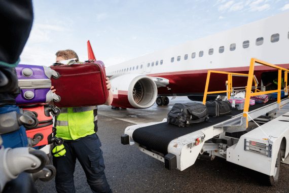 A baggage handler loading luggage onto an aeroplane