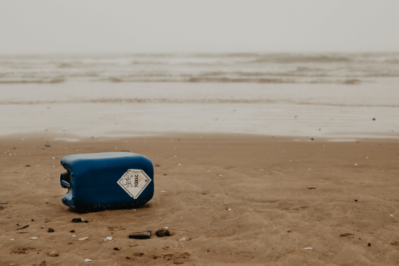 A blue plastic container on a beach with Toxic written on it