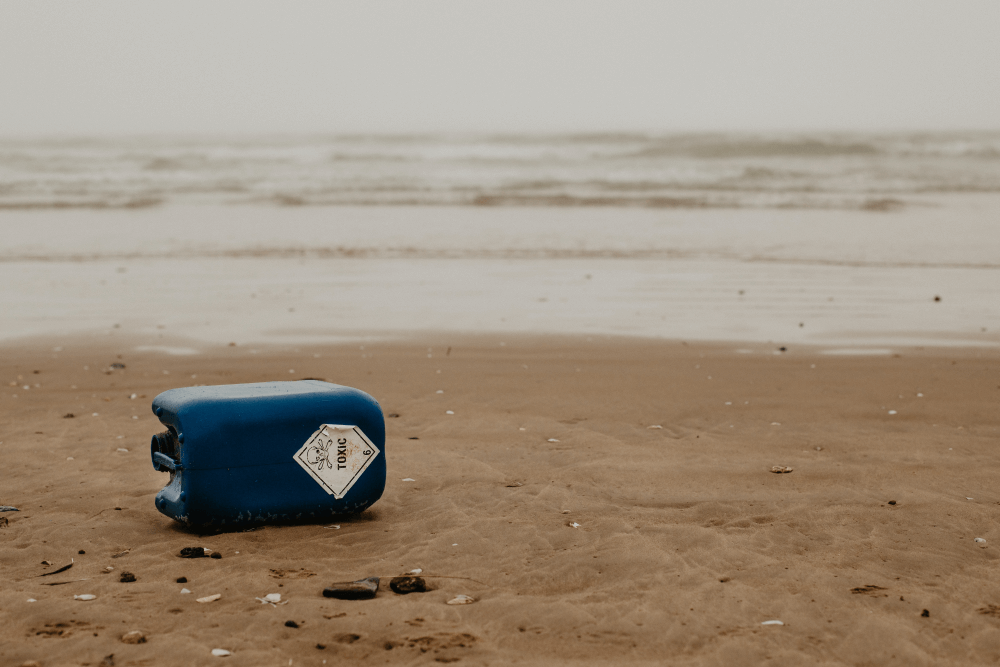 A blue plastic container on a beach with Toxic written on it