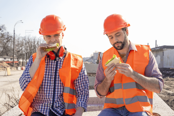 Two construction workers eating sandwiches