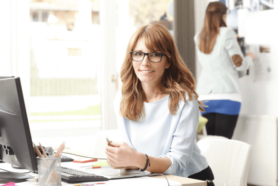Female manager wearing glasses sat behind a desk