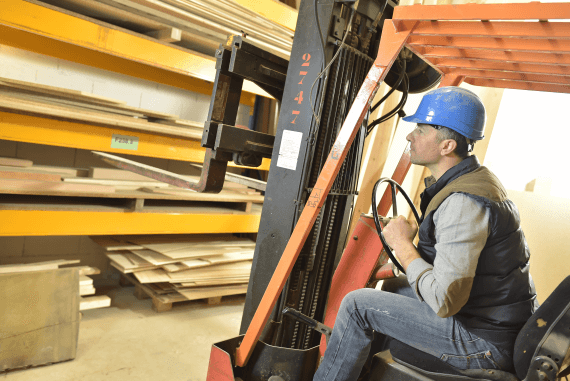 A man driving and operating a forklift