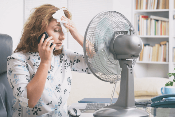 An office worker too hot trying to cool off with a fan
