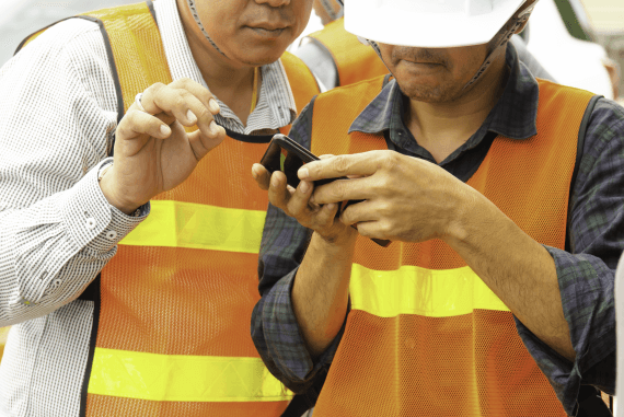 Two construction workers looking at a mobile phone
