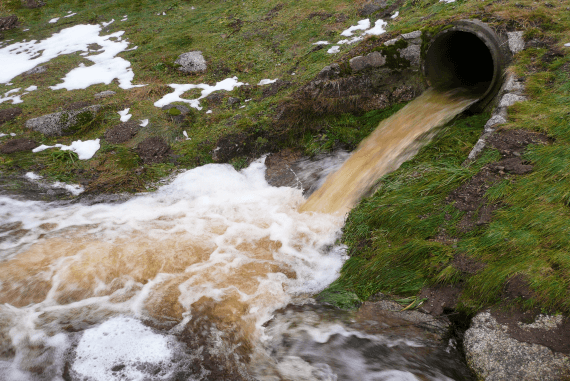 Polluted water being discharged from a sewer pipe into a river