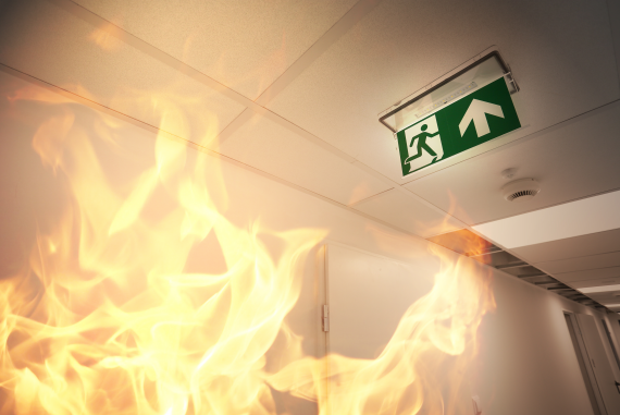 A fire in the workplace image with an emergency exit sign